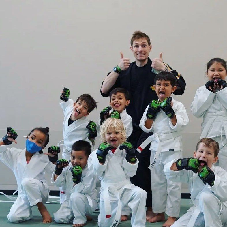A group of young children in karate uniforms are posing for a picture.