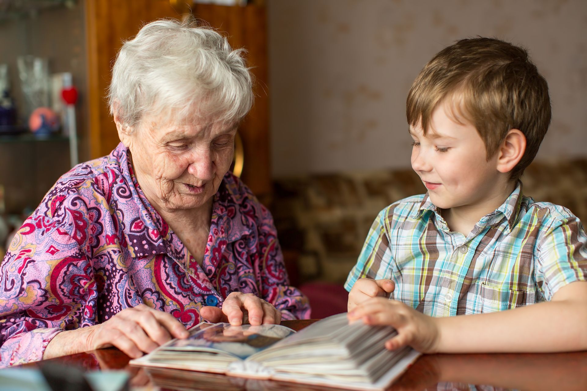 elderly woman and grandson looking at photo album