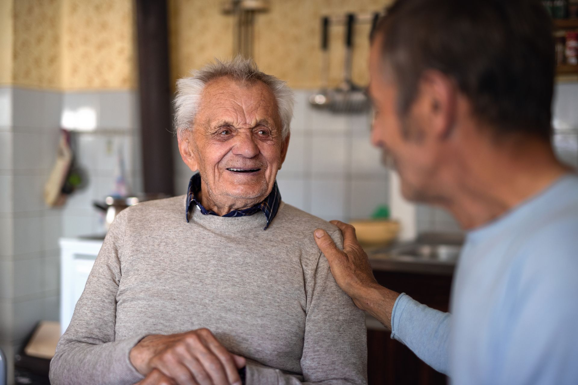 elderly man and son in kitchen reminiscing about their lives