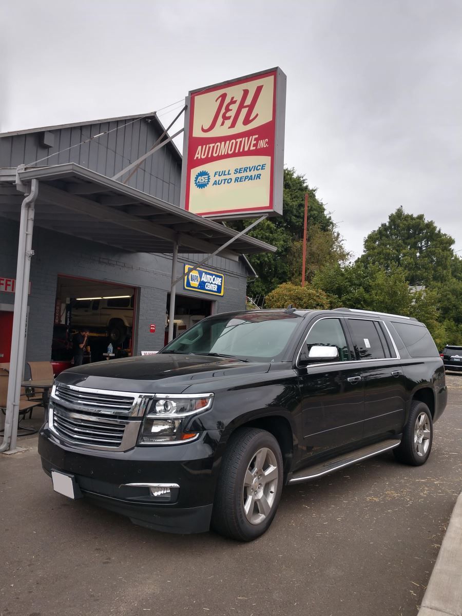 A black suv is parked in front of an automotive shop. | J&H Automotive Inc