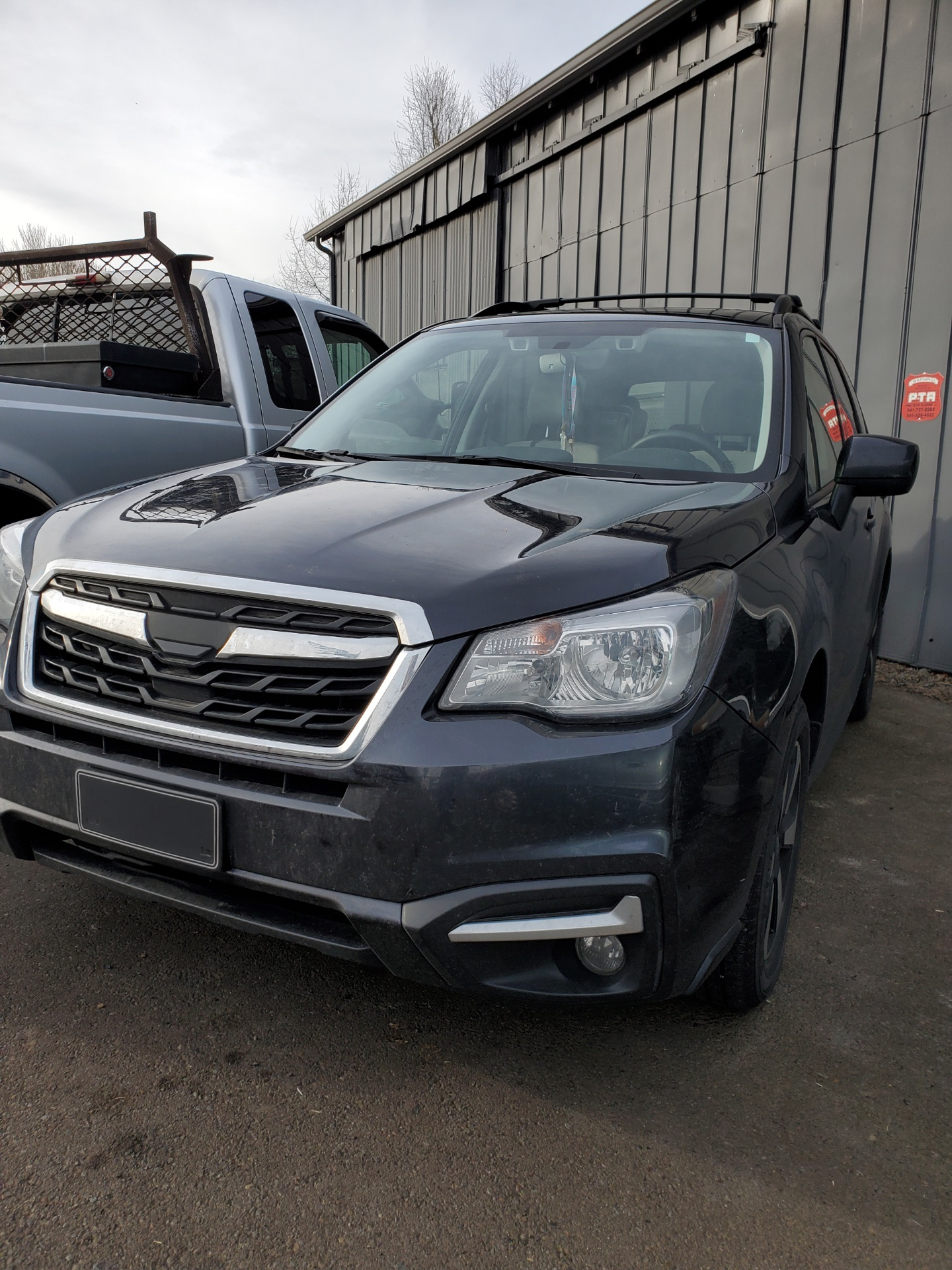 A black subaru forester is parked in front of a building. | J&H Automotive Inc