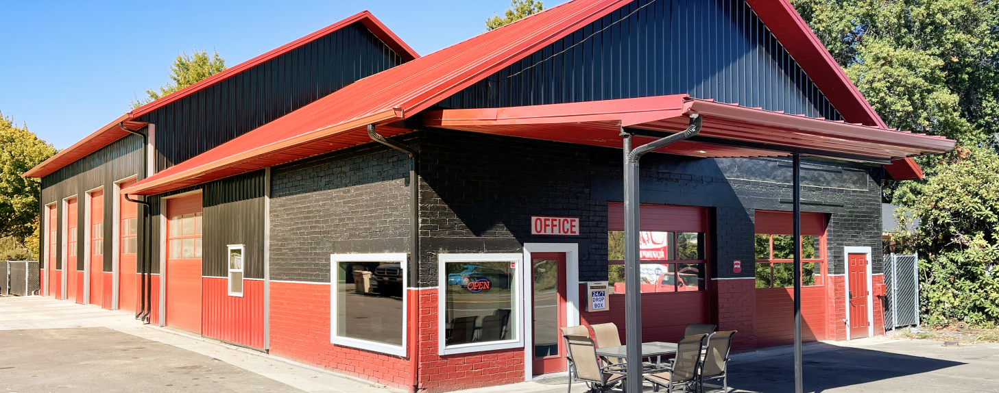 A red and black building with a red roof and a porch. | J&H Automotive Inc