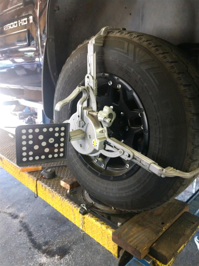 A car is being adjusted on a lift in a garage. | J&H Automotive