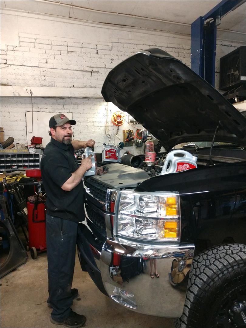 A man is working on a truck in a garage with the hood open | J&H Automotive