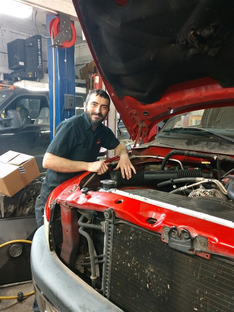 A man is leaning on the hood of a red truck | J&H Automotive