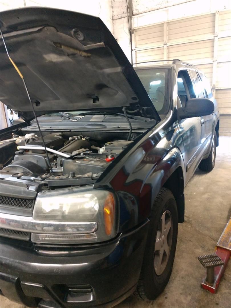 A black truck with the hood up is parked in a garage. | J&H Automotive