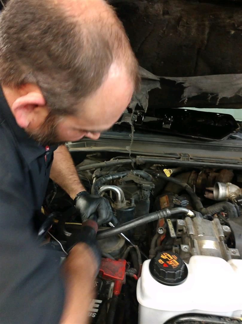 A man is working under the hood of a car. | J&H Automotive