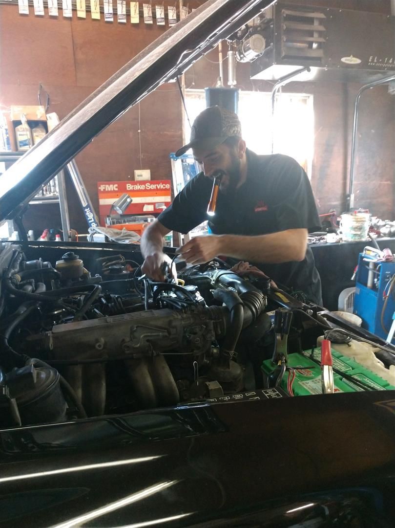 A man is working on the engine of a car in a garage. | J&H Automotive