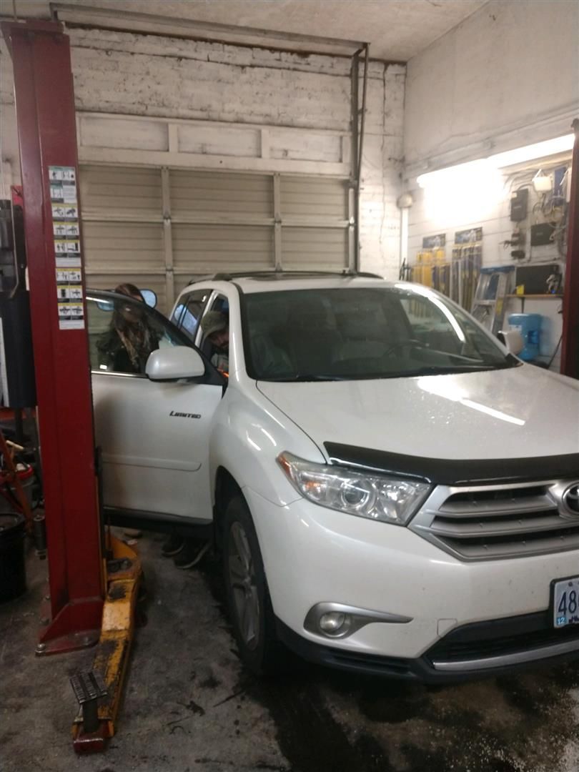 A white car is sitting on a lift in a garage. | J&H Automotive