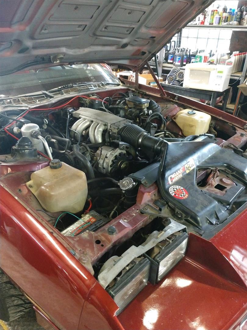 The engine of a red car is being worked on in a garage. | J&H Automotive