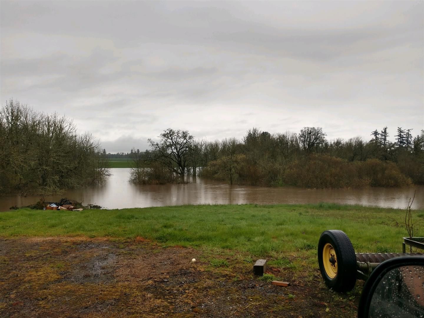 A tractor is parked in front of a flooded field. | J&H Automotive