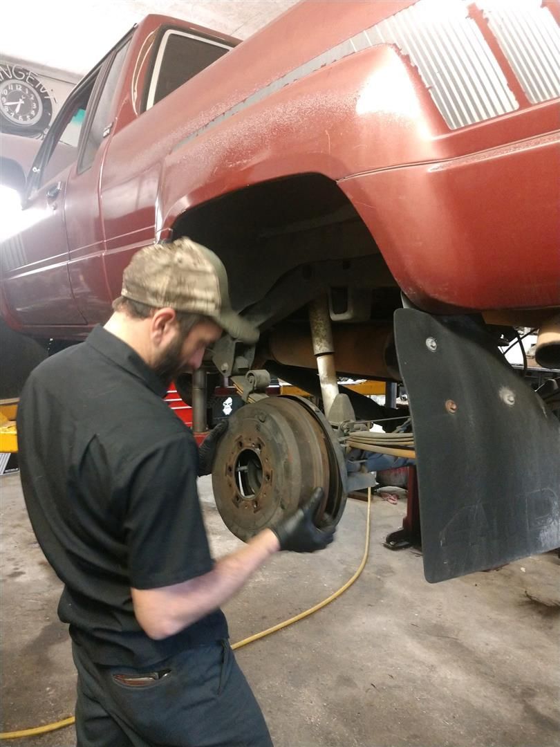 A man is working on a red truck in a garage | J&H Automotive