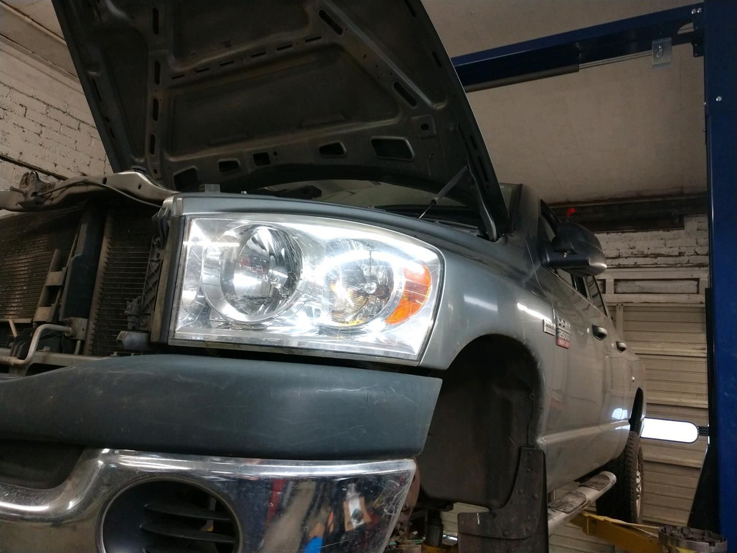 A truck with the hood up is on a lift in a garage. | J&H Automotive