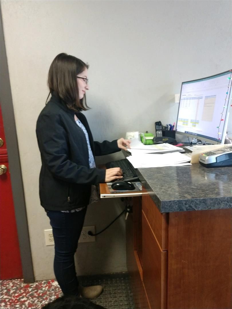 A woman is standing at a desk with a computer on it | J&H Automotive