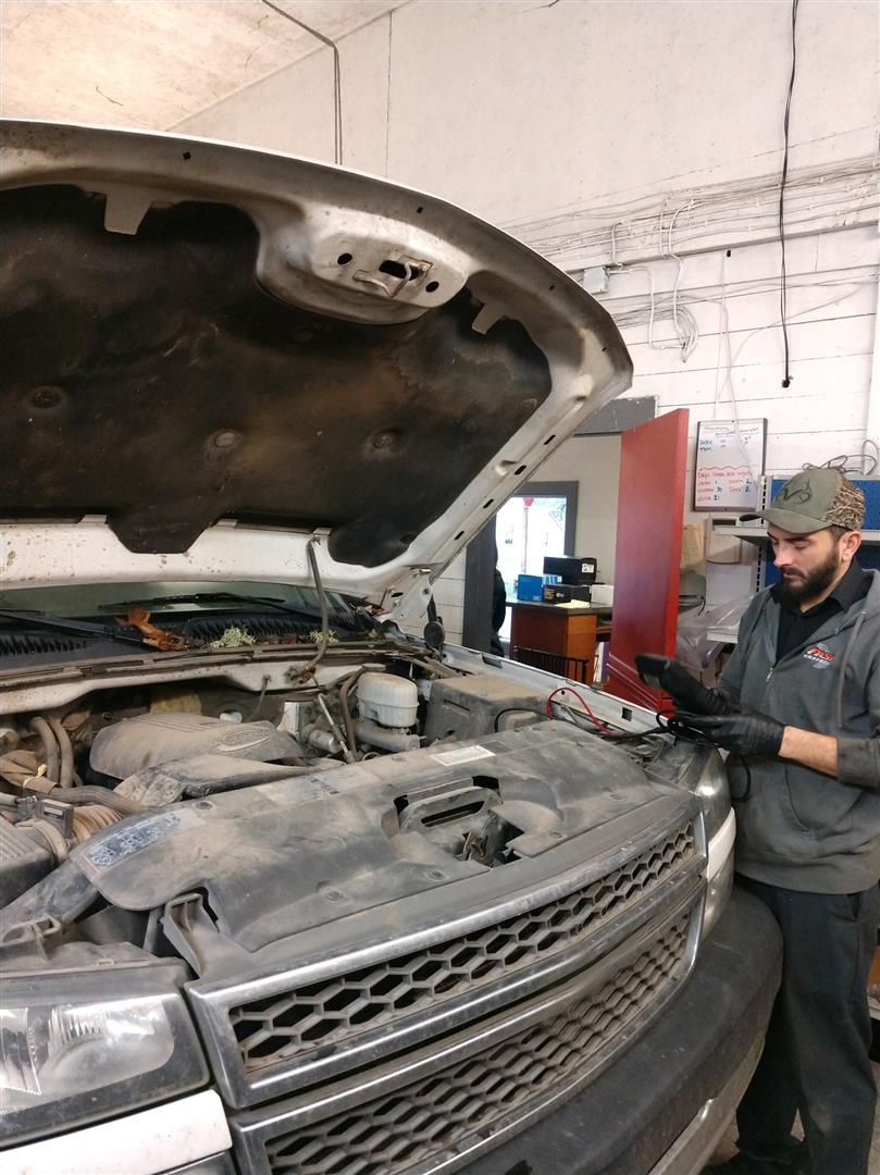 A man is working on a truck in a garage with the hood open. | J&H Automotive