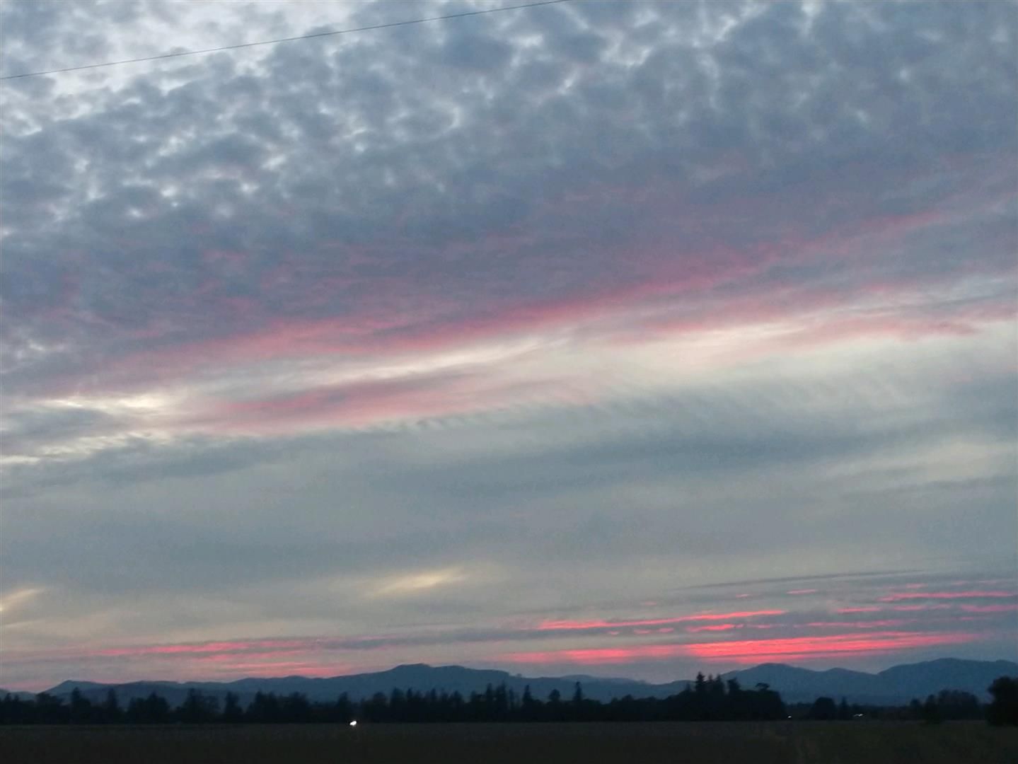 A sunset over a field with mountains in the background | J&H Automotive