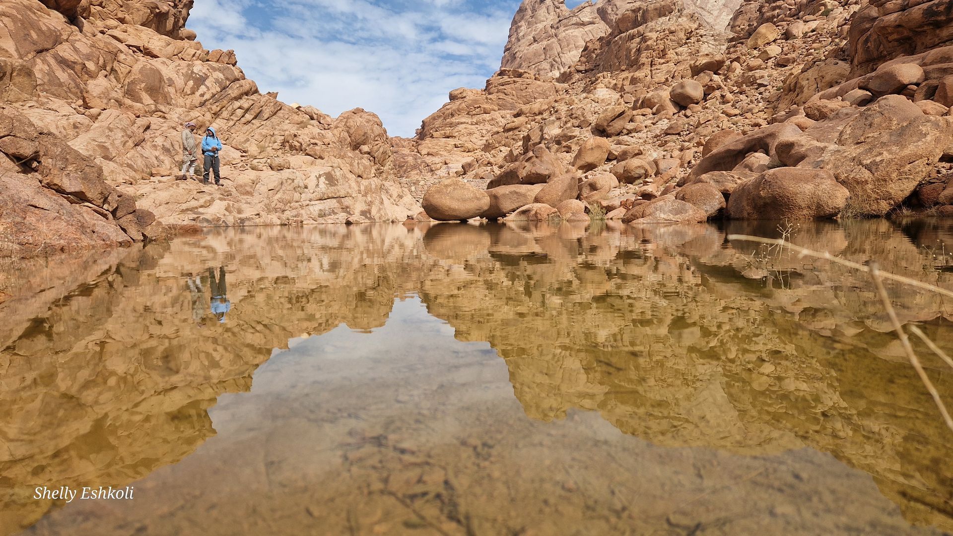 Building illuminated at night with arched doorways, people in front.