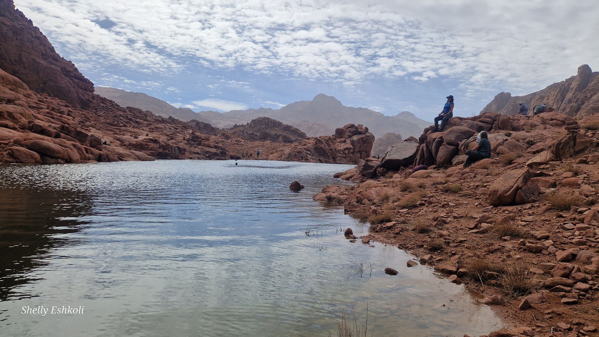 Building illuminated at night with arched doorways, people in front.