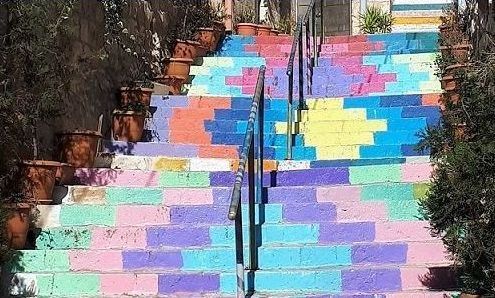 Building illuminated at night with arched doorways, people in front.