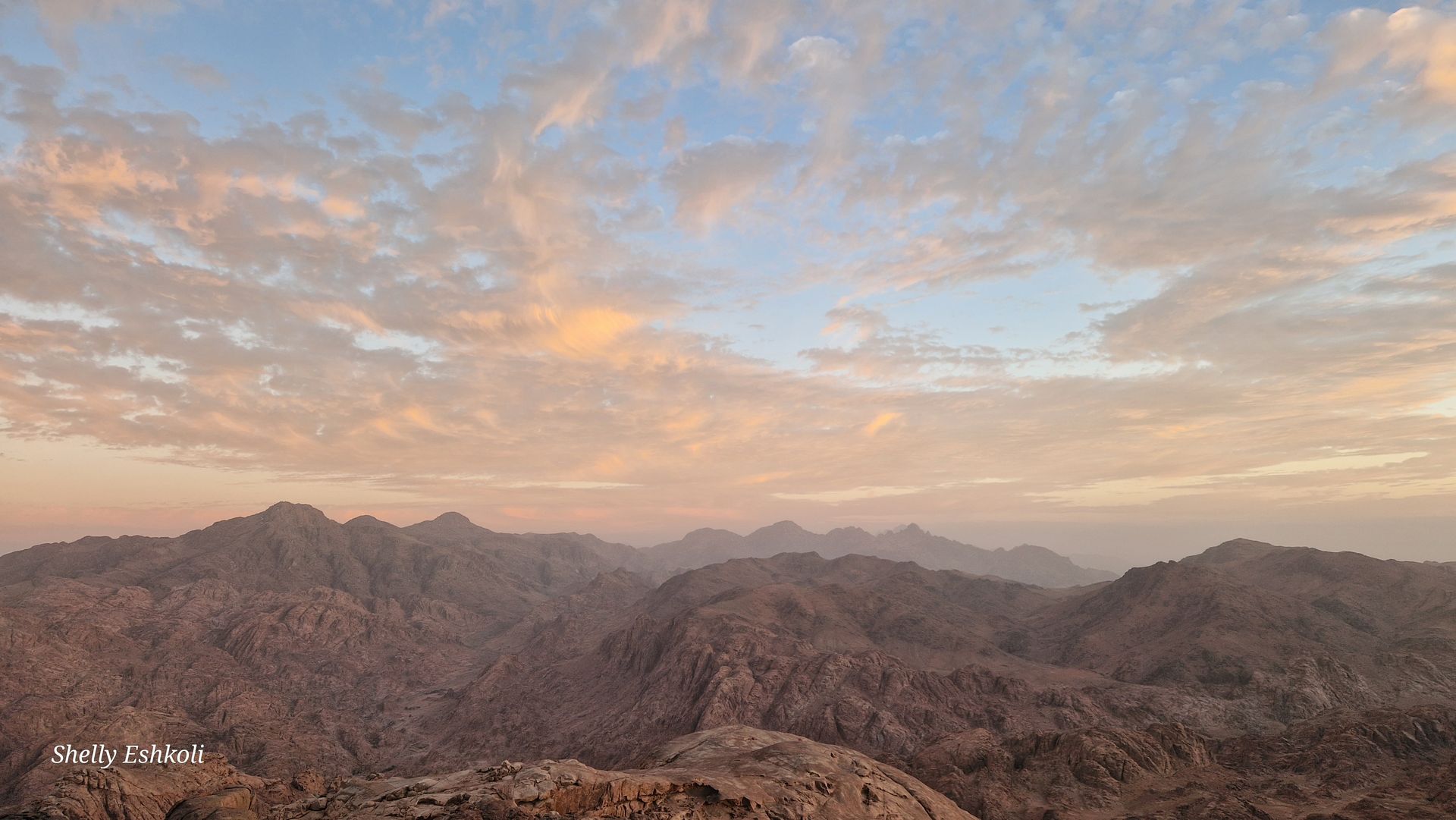 Building illuminated at night with arched doorways, people in front.