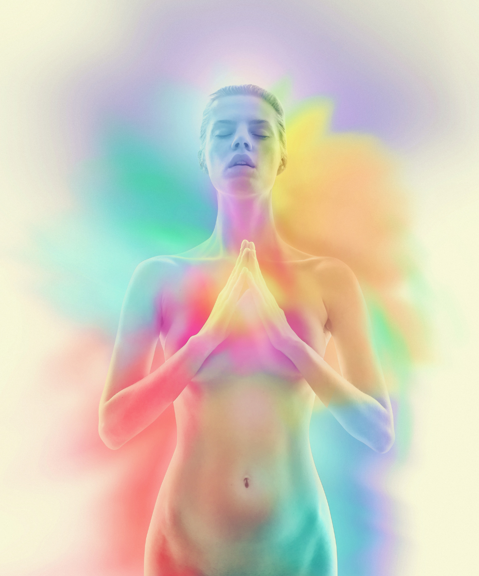 A woman wearing a necklace and bracelet is holding her hands to her chest.