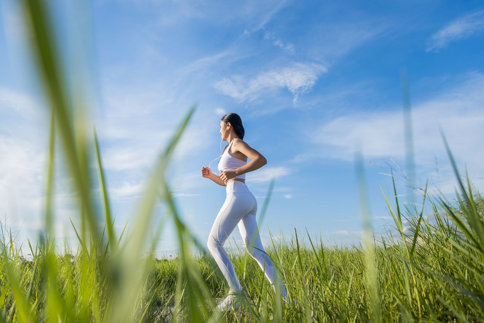 a woman in white running through a grassy field