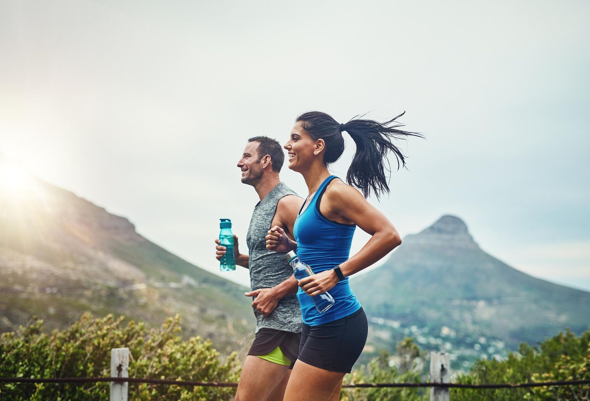 a man and a woman are jogging in front of a mountain
