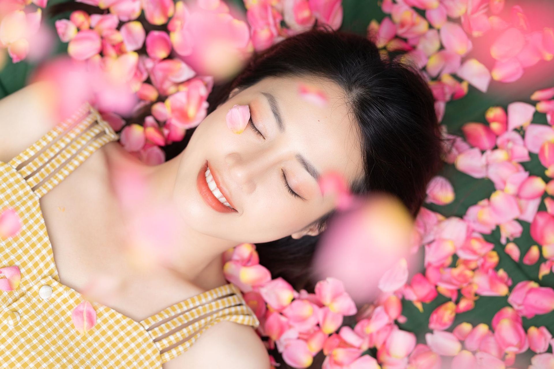 a woman with her eyes closed is surrounded by pink petals