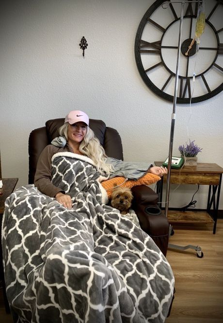 a woman in a pink nike hat is sitting in a chair with a dog