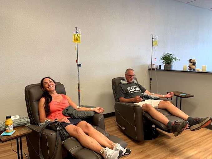a man and a woman are sitting in chairs with iv drips in their hands .