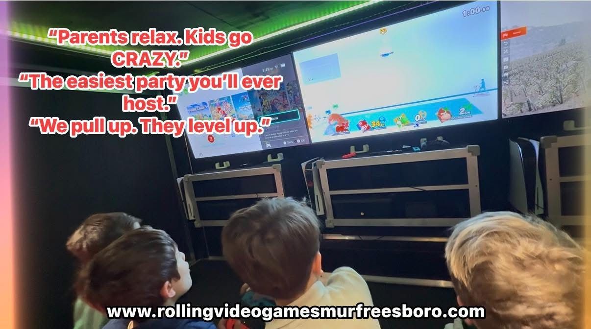 Children watch large gaming screens inside a mobile video game trailer, with promotional text and a website URL visible.