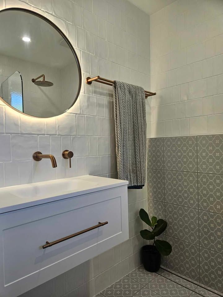 A bathroom with a sink , mirror and shower.