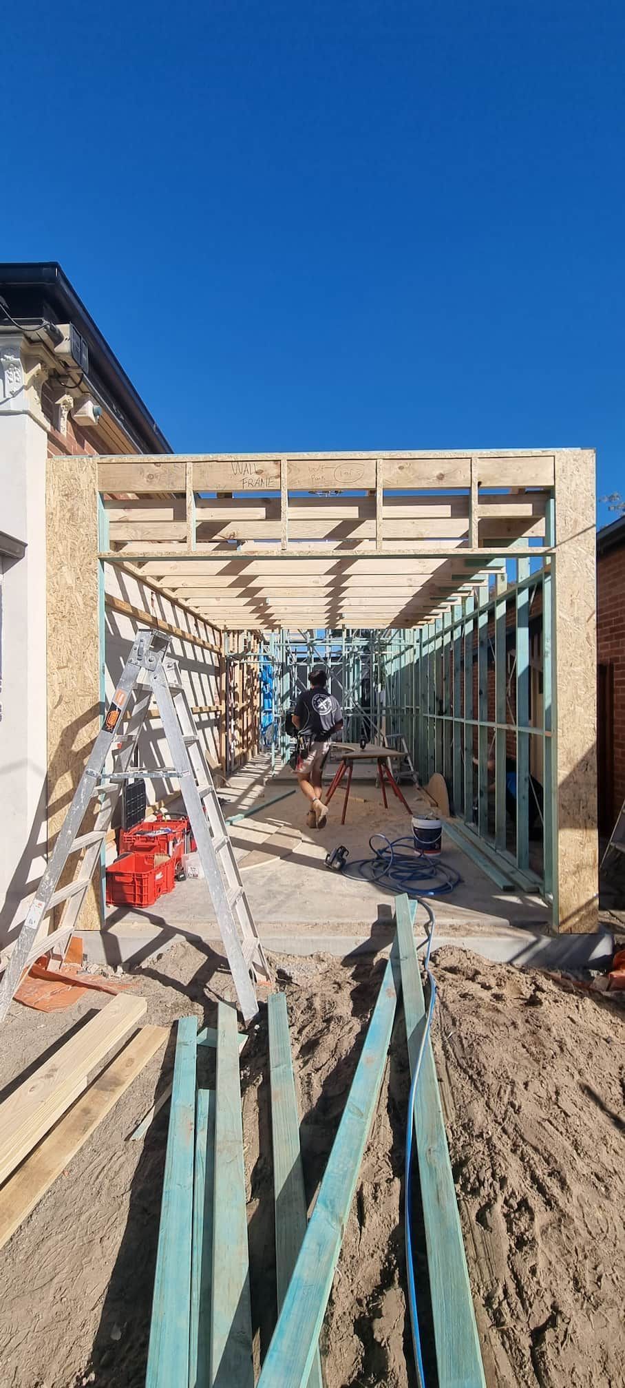 A wooden structure is being built next to a house.