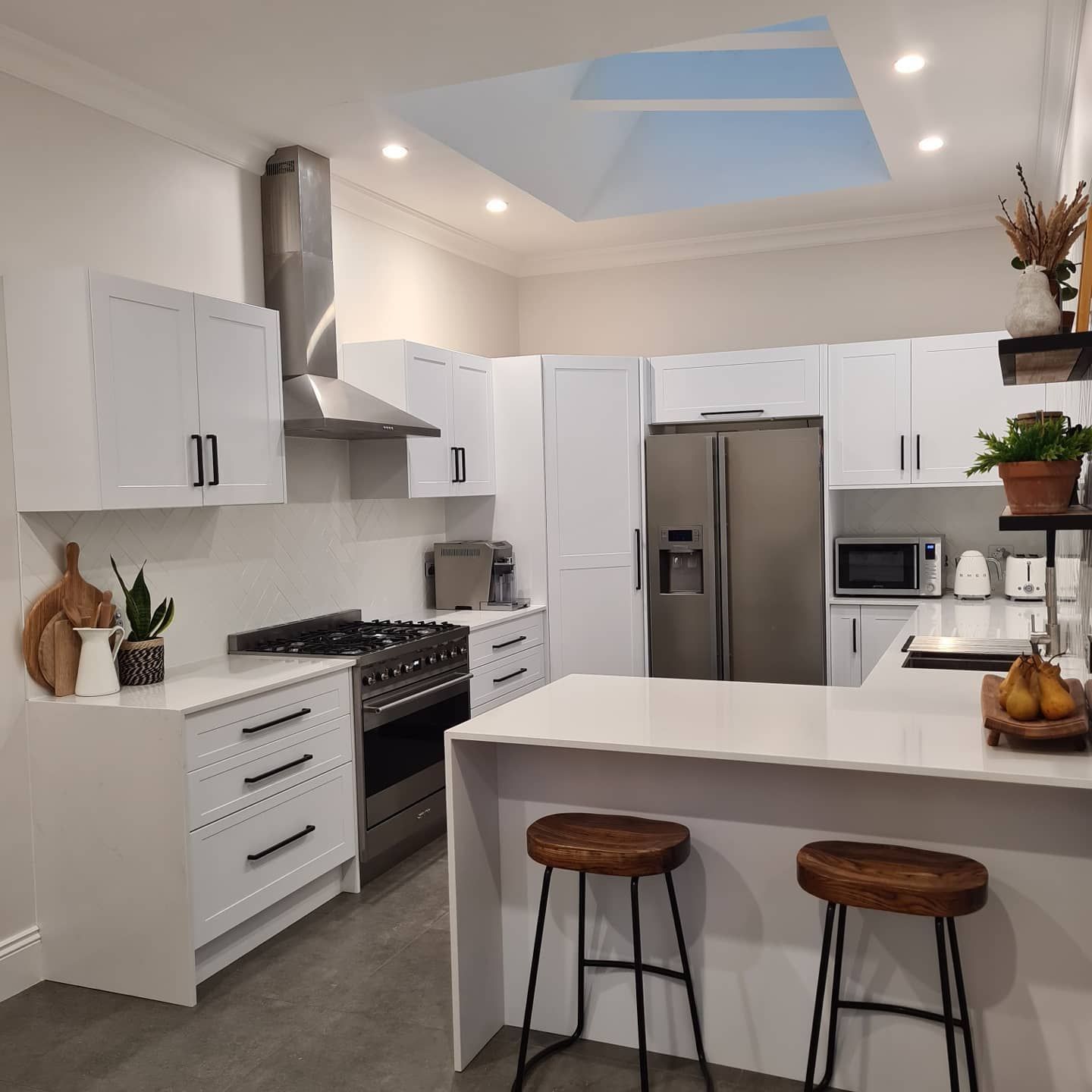 A kitchen with white cabinets , stainless steel appliances , a refrigerator and a stove.
