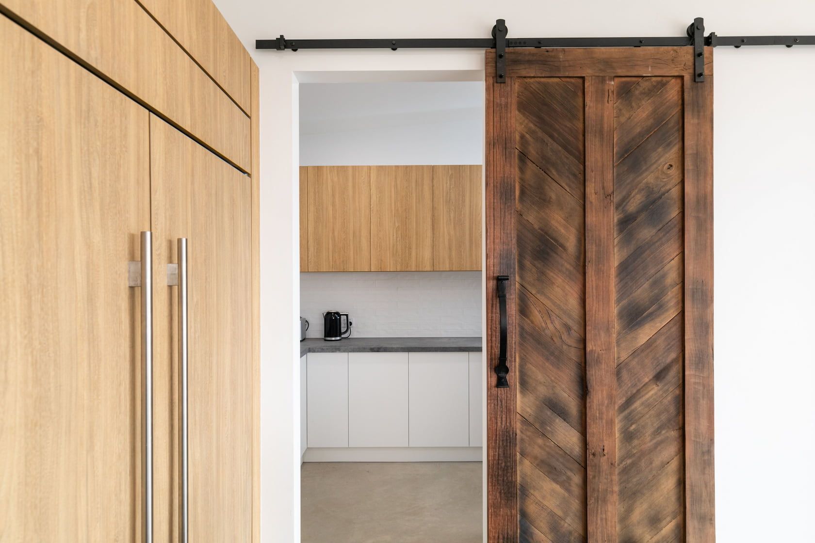 A wooden sliding barn door is open to a kitchen.