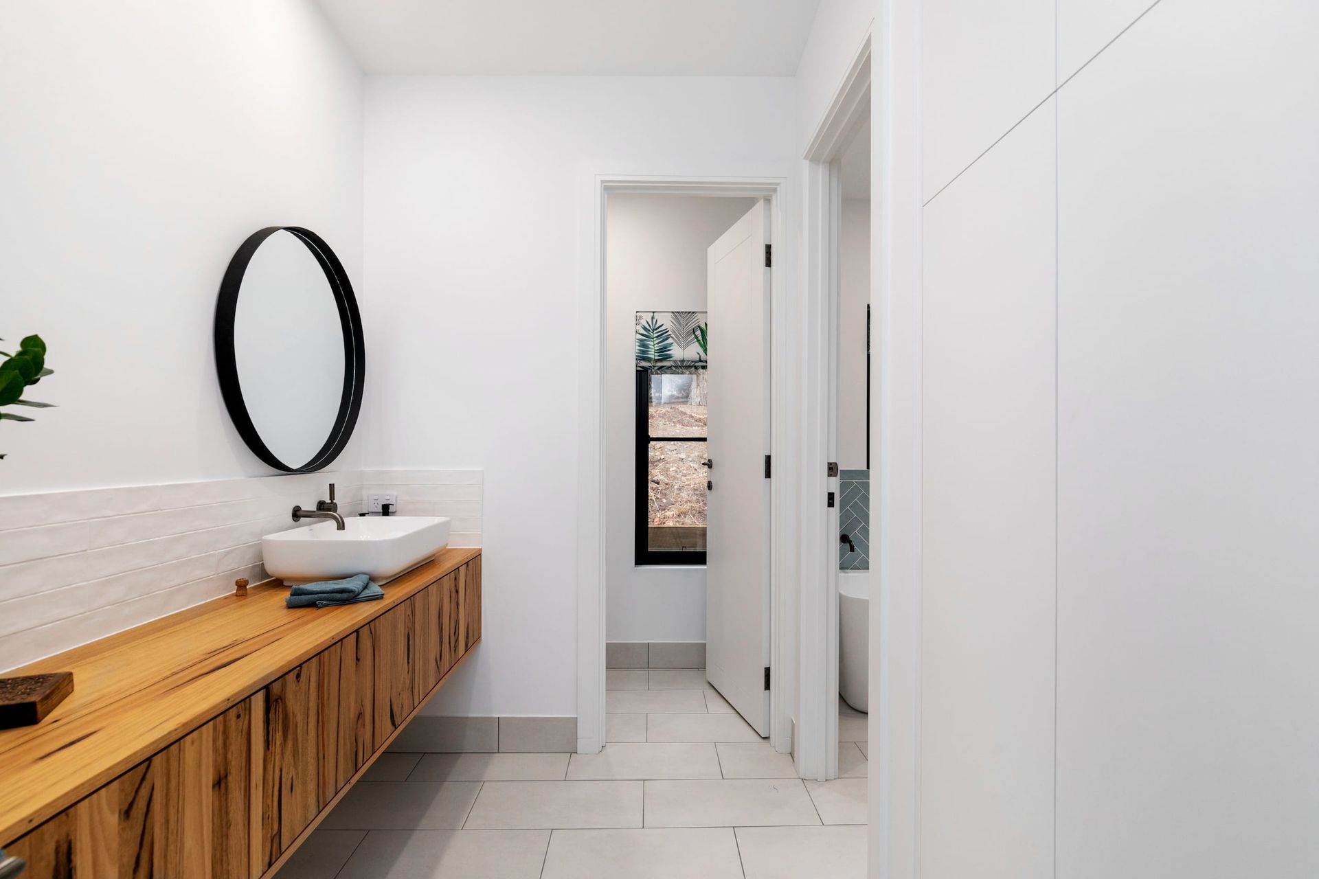 A bathroom with a sink , mirror , and wooden cabinets.