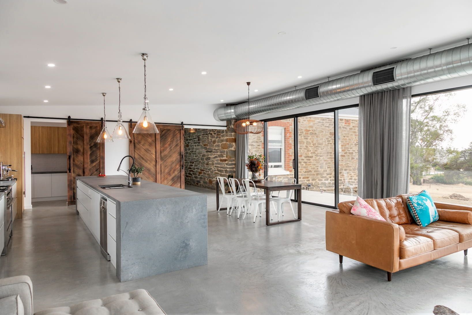 A living room with a couch , table , chairs and sliding glass doors.
