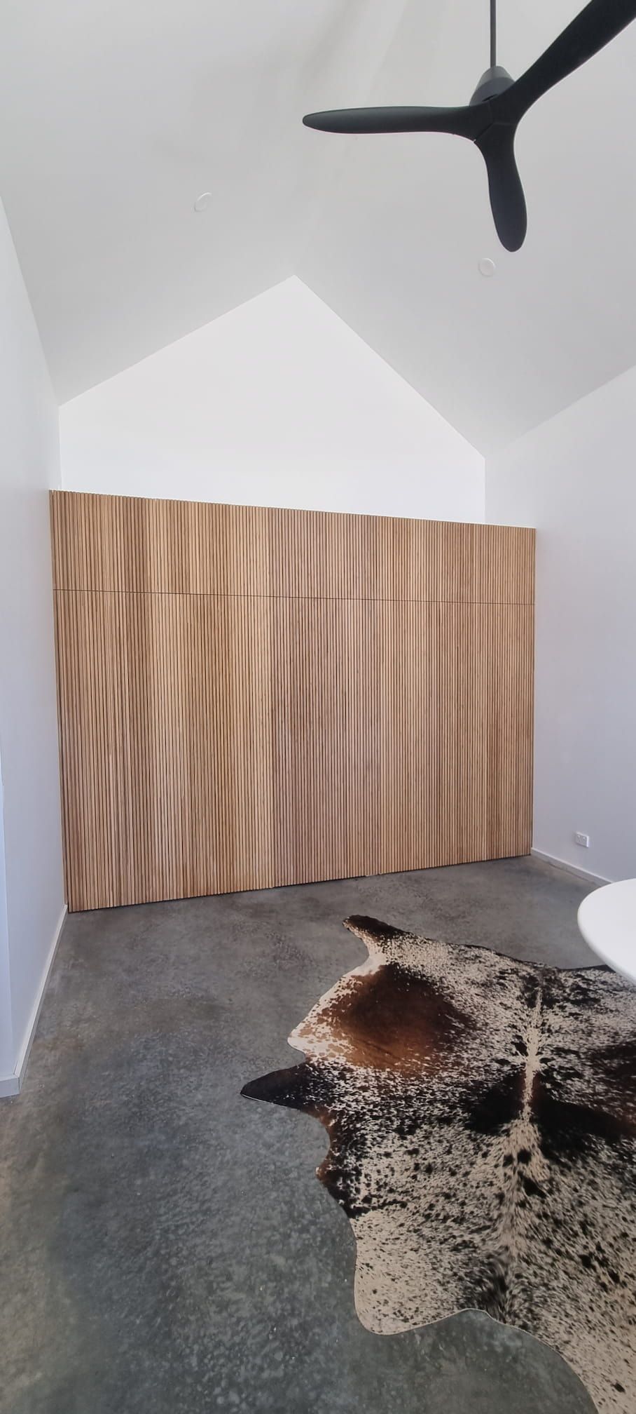 A room with a cowhide rug and a ceiling fan.