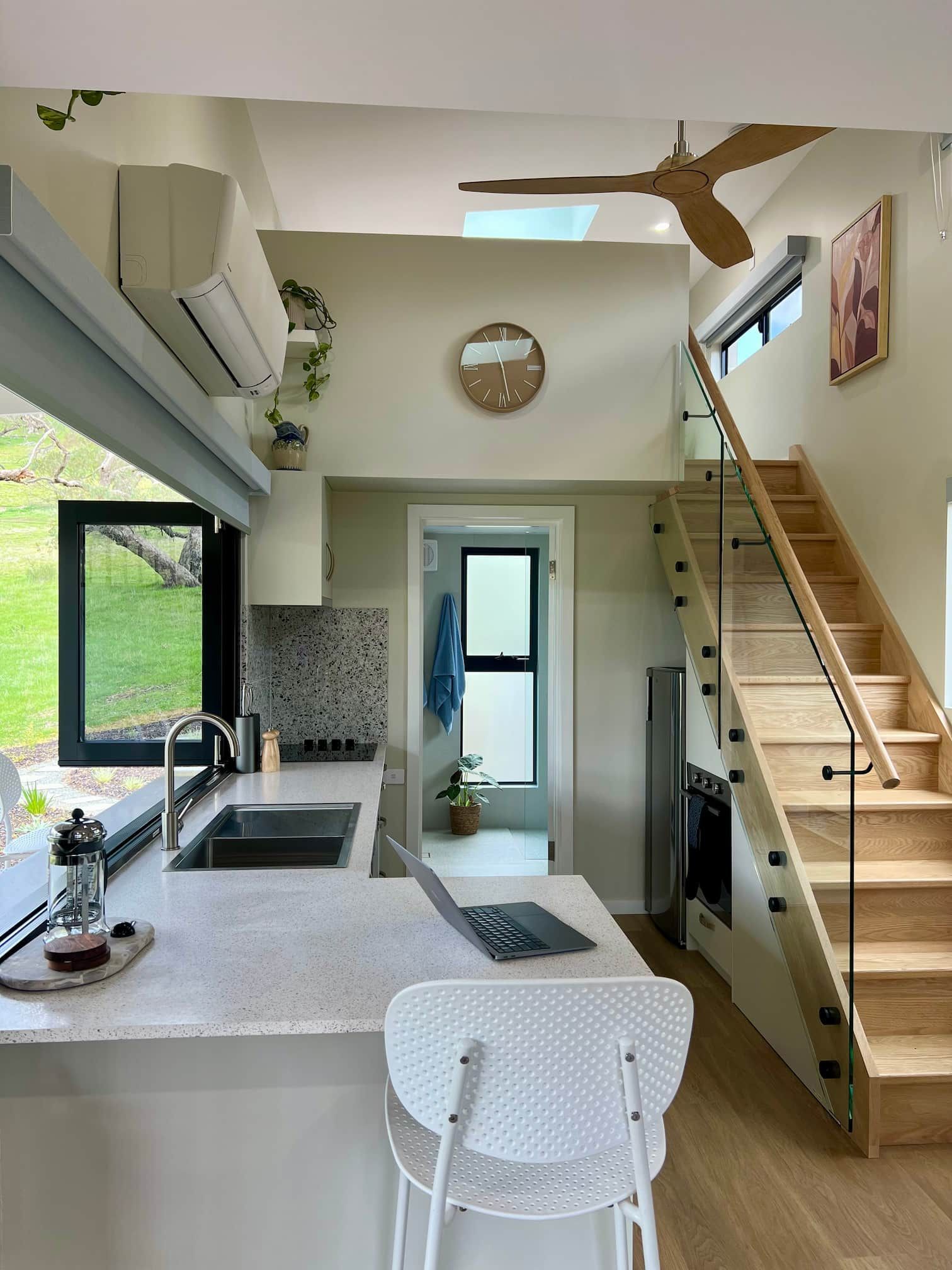 A kitchen with a sink , stairs and a ceiling fan.