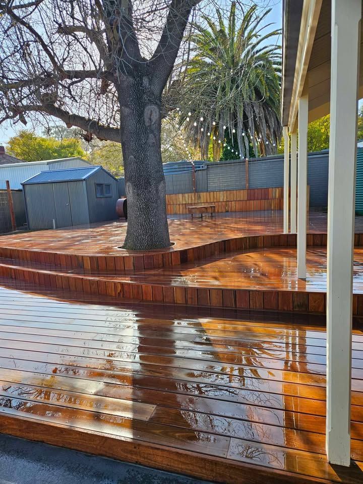 A large wooden deck with a tree in the background.