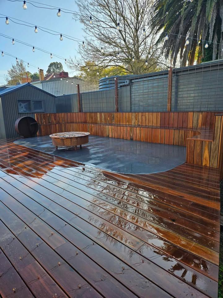 A wooden deck with a fire pit in the middle of it.