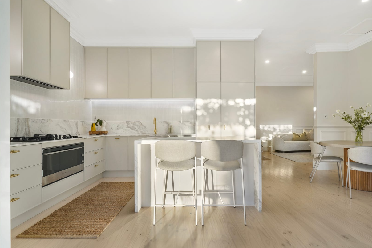 A kitchen with white cabinets , stainless steel appliances , a table and chairs.