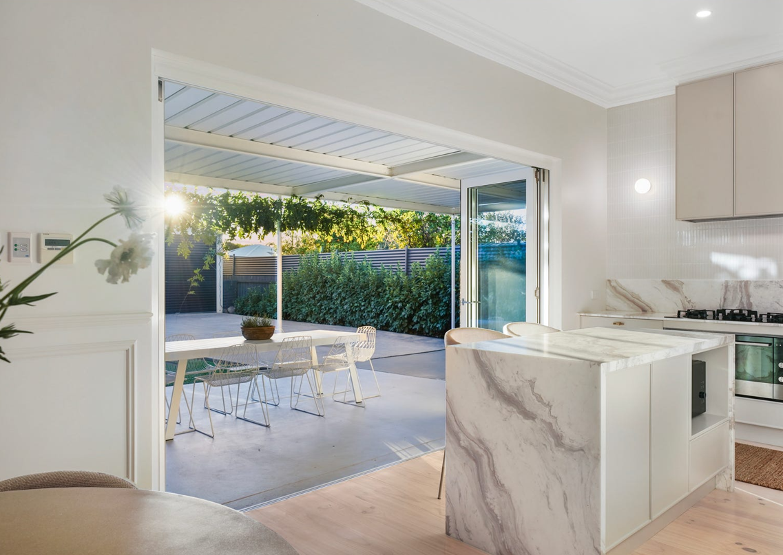 A kitchen with a marble counter top and sliding glass doors leading to a patio.