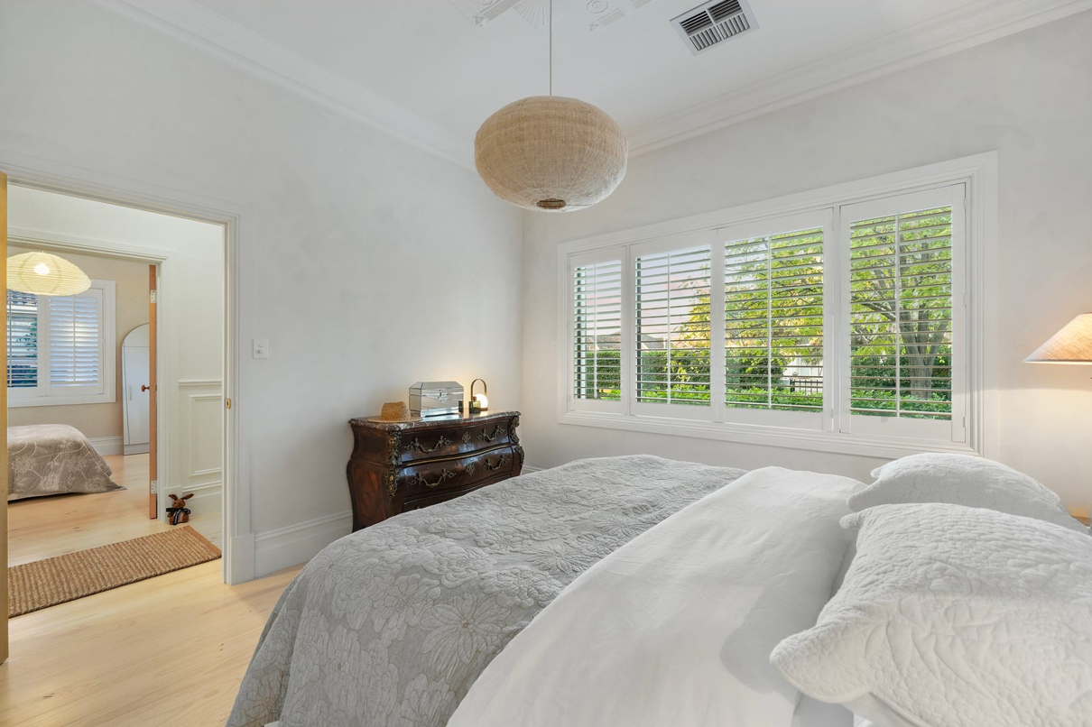 A bedroom with a large bed , dresser , and window.