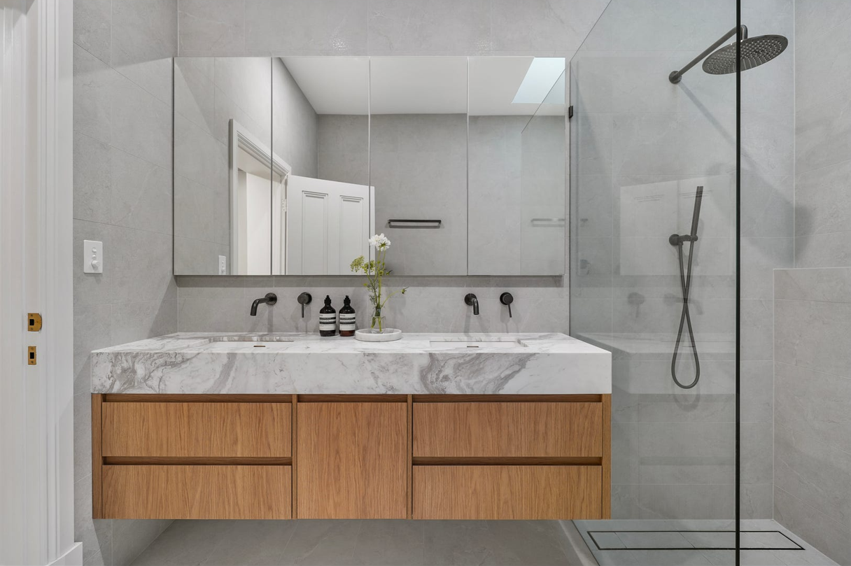 A bathroom with two sinks and a walk in shower.