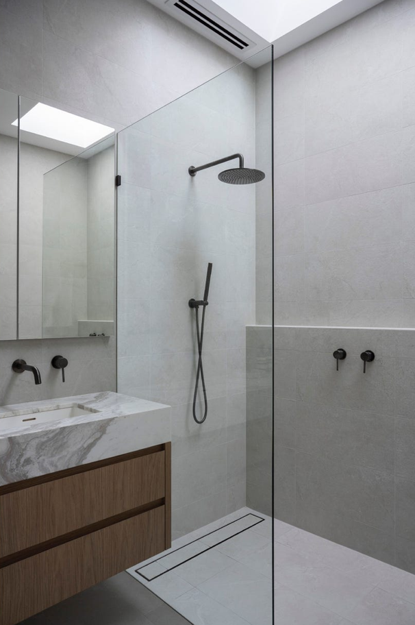A bathroom with a walk in shower and a sink