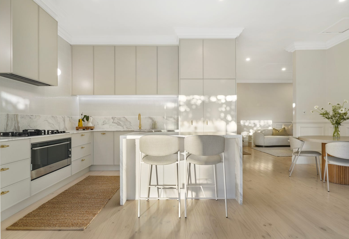 A kitchen with white cabinets and wooden floors