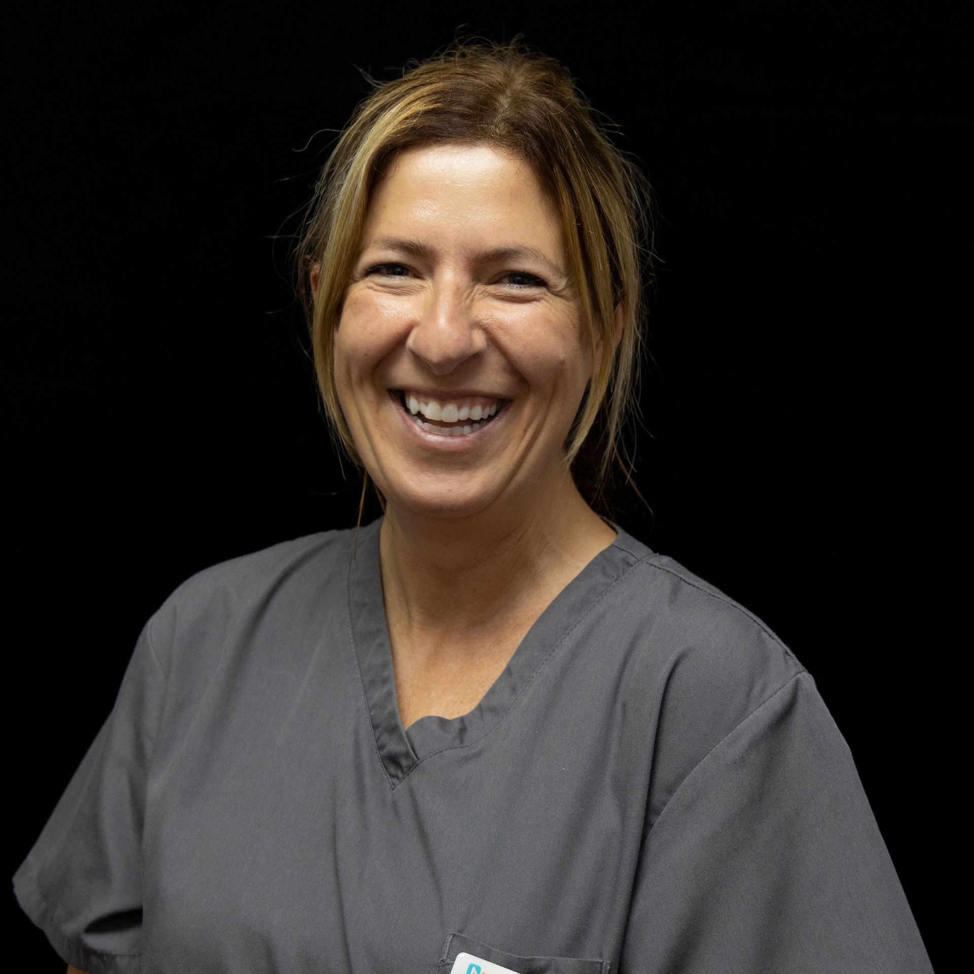 A woman in a scrub top is smiling for the camera.