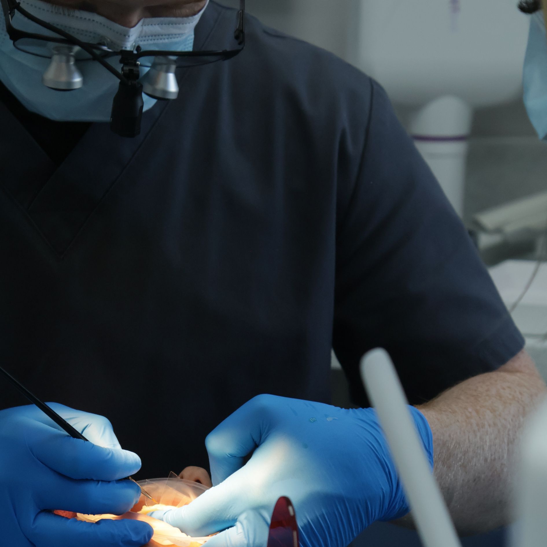 A dentist is examining a patient 's teeth and completing composite bonding. 