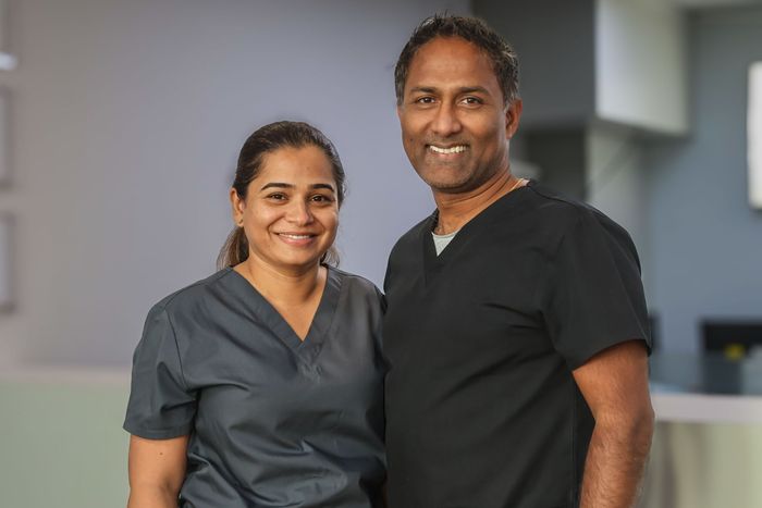 Two dental professionals, a woman and man, smiling for the camera. 